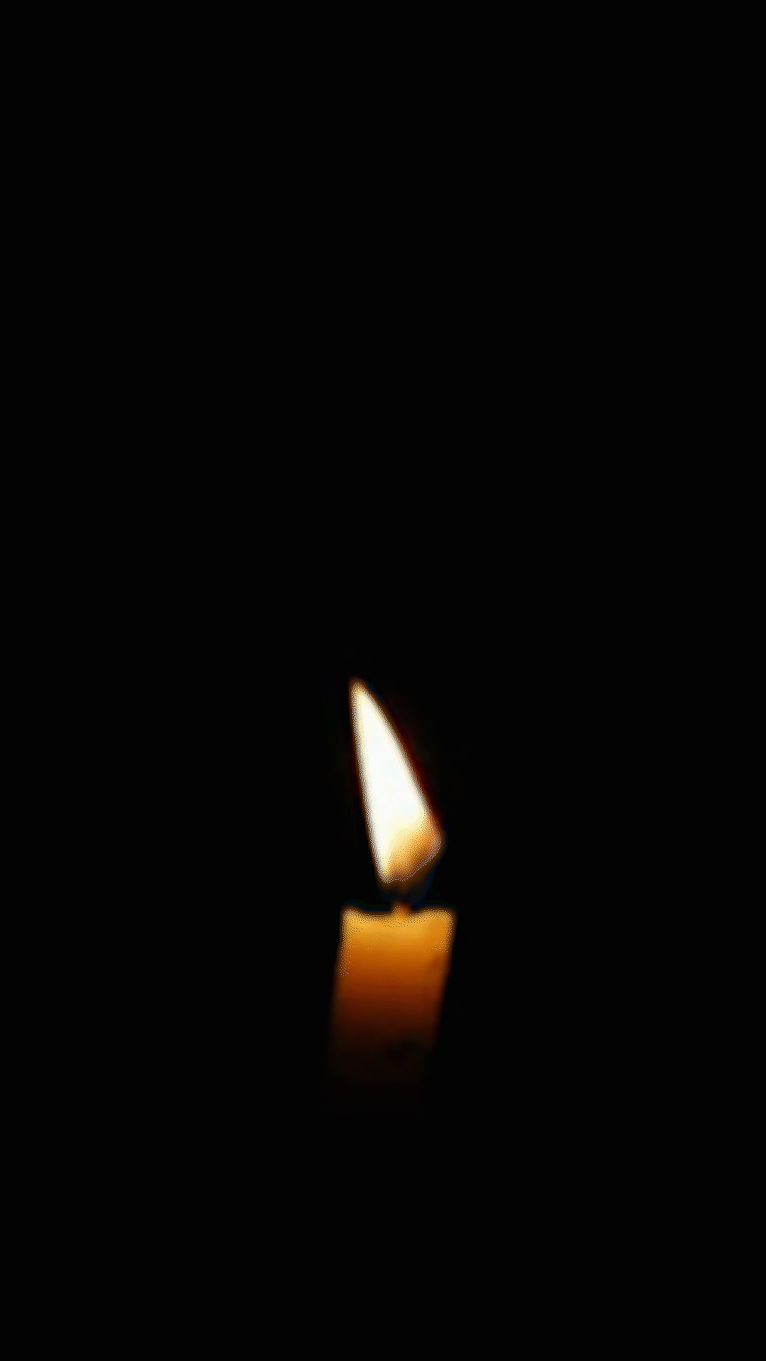 A candle infrot of a dark background